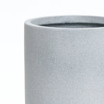 A gray round planter with a smooth texture, embodying modern minimalist decor, is showcased against a plain white background. Its design ensures it doubles as a weather-resistant planter, perfect for indoors or out.