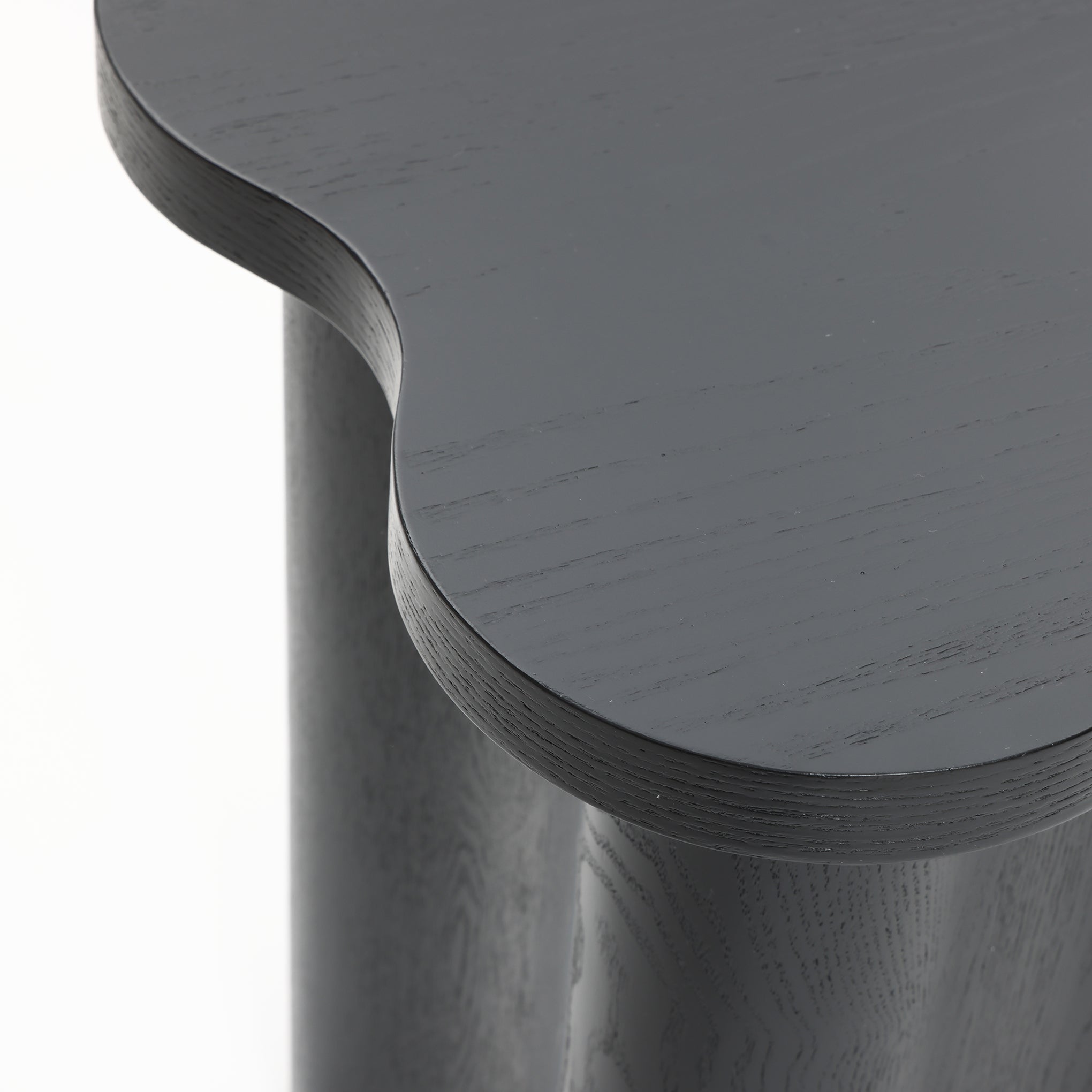 Close-up view of a modern-style side table with a dark gray, black cloverleaf-shaped top and cylindrical legs, crafted from premium MDF wood.