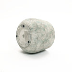 A LuxenHome Rustic Multi-Color Cement 18.3-Inch Round Planter, with textured wavy horizontal lines in gray and light green, reminiscent of a ceramic vase, lies on its side against a white background. It features a circular flat bottom with three small black feet.