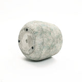 A LuxenHome Rustic Multi-Color Cement 18.3-Inch Round Planter, with textured wavy horizontal lines in gray and light green, reminiscent of a ceramic vase, lies on its side against a white background. It features a circular flat bottom with three small black feet.