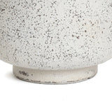 Close-up of a textured, speckled ceramic planter with a round base, exuding an antique charm and displaying a rough, off-white surface.