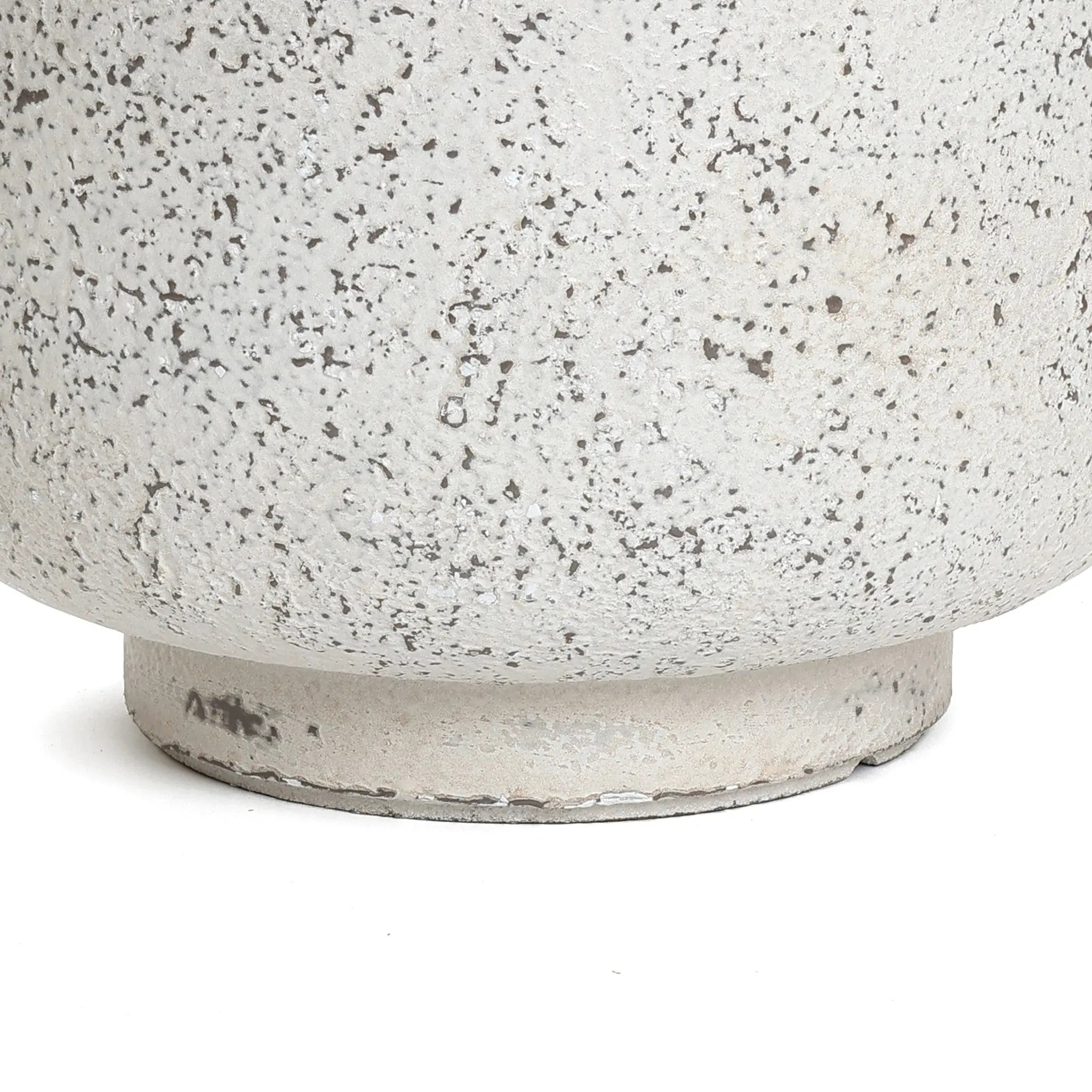 Close-up of a textured, speckled ceramic planter with a round base, exuding an antique charm and displaying a rough, off-white surface.