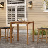 Two wooden stools and a charming square table crafted from FSC-Certified Acacia Wood are on a patio in front of a beige building with a window. Lanterns are mounted on the wall, and plants flourish in the background, creating an inviting outdoor space.