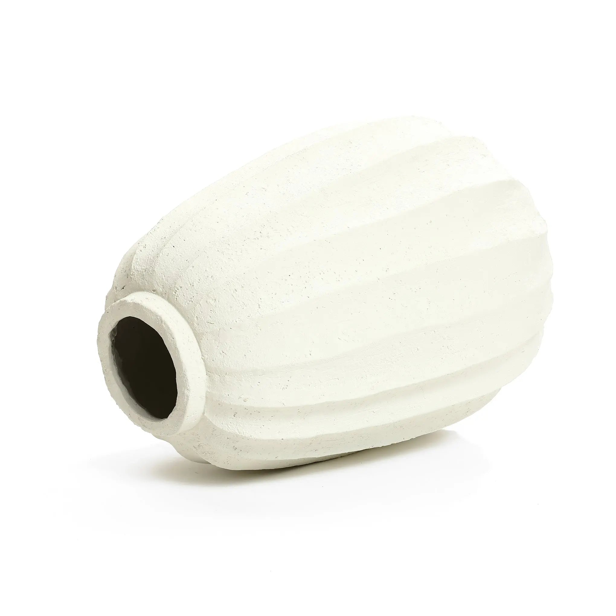 A modern white vase, with its textured ceramic design, rests elegantly on its side against a plain background, serving as the perfect artistic centerpiece in any minimalist home decor.