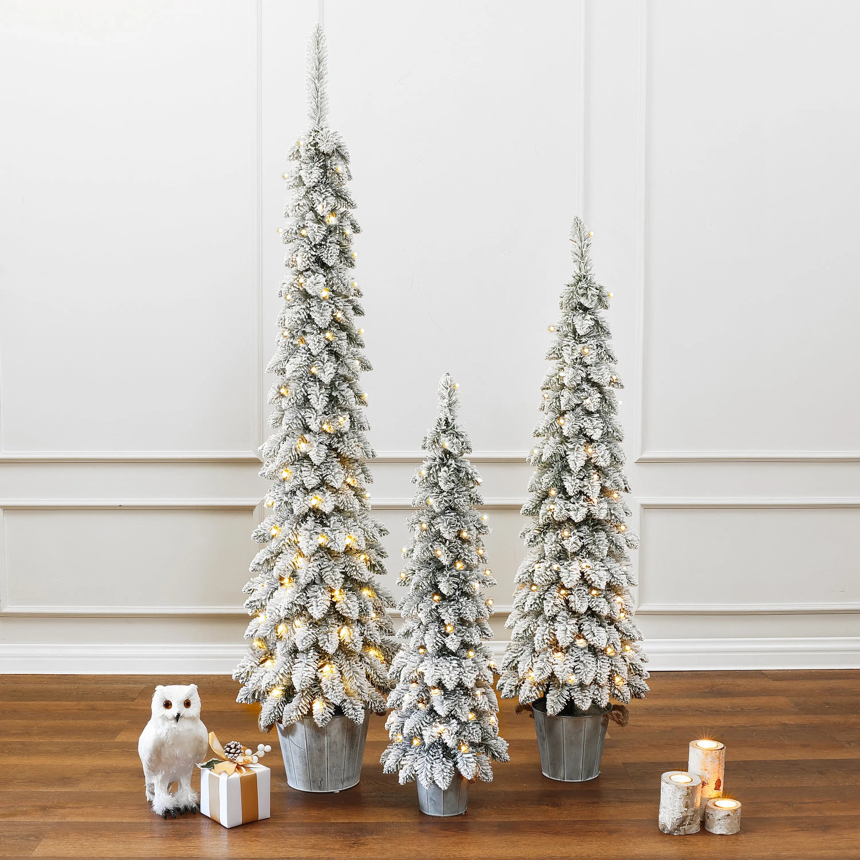 pre-lit-snow-flocked-small-christmas-tree-set-of-3-on-the-ground-with-gift-box-and-candle