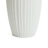 Close-up of the base of a tall, white ceramic vase with vertical ridges, embodying modern abstract sculpture. This decorative piece seamlessly enhances any contemporary home decor against its pristine white background.