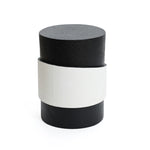 A cylindrical black object with a unique white irregular pattern wrapped around the middle, set against a plain white background.