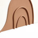 Close-up of three nested arches in beige relief against a white textured wall surface, reflecting the essence of modern art home decor.