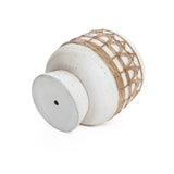 A white, round ceramic vase with a wide body, lying on its side, exudes Bohemian style with a pattern of tan rope artfully wrapped around the upper portion.
