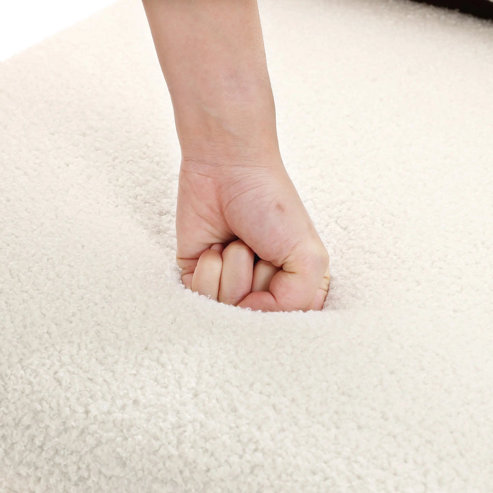 A close-up shows a hand pressing into the plush, white surface of the LuxenHome Lorenzo boucle upholstered wood frame armless accent chair, creating an indentation. The high-density foam offers cushiony comfort and softness with mid-century allure.