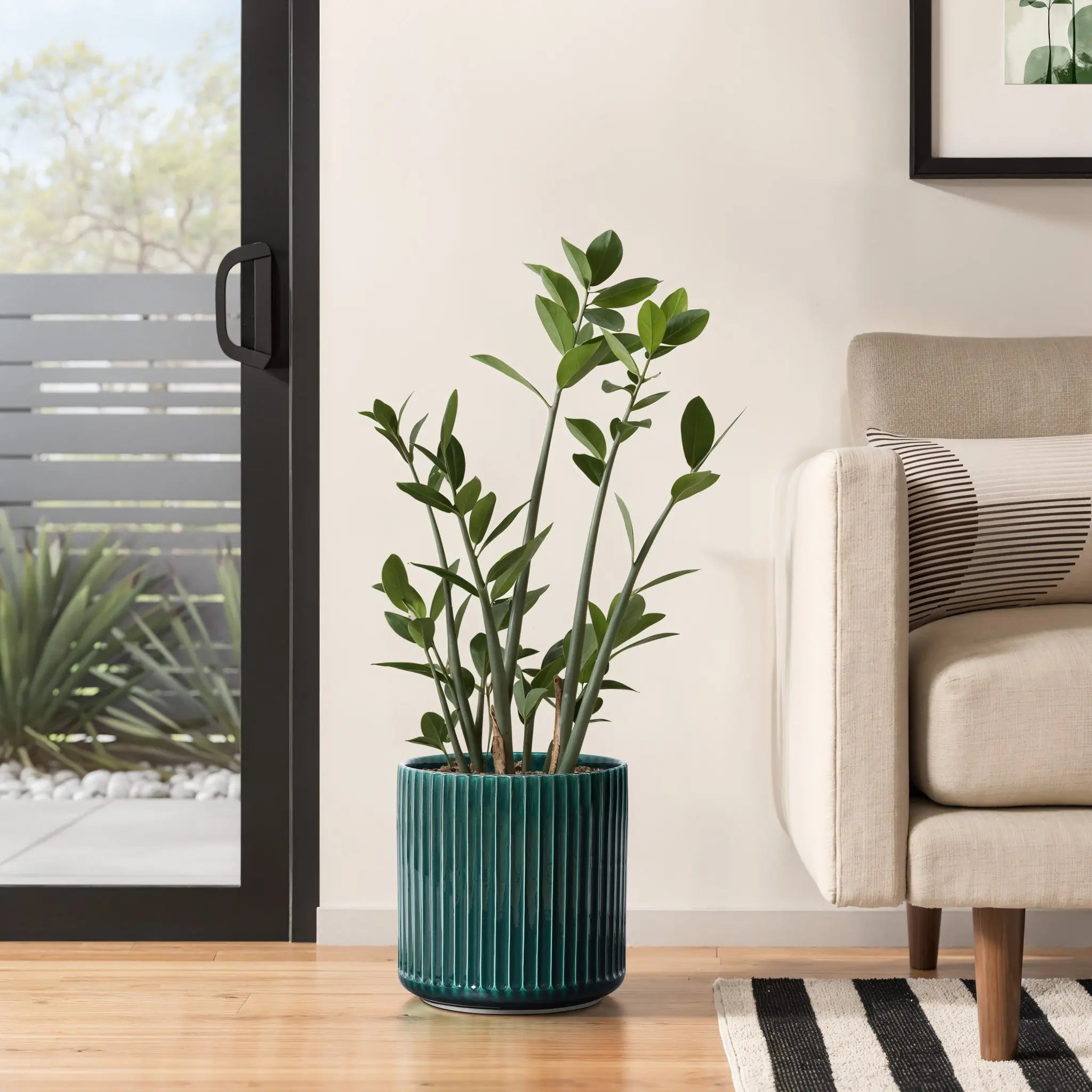A lush green plant flourishes in a LuxenHome Jade green ribbed glazed round ceramic planter on a wooden floor beside a beige sofa. Positioned near a sliding glass door, it offers garden views, creating an indoor modern plant paradise thats bright and refreshing.