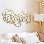 Geometric metal wall art with overlapping gold frames hangs above a white couch adorned with patterned pillows, while a floor lamp with hanging glass ornaments adds a touch of elegance nearby.