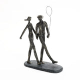A modern resin sculpture of a couple walking hand in hand. The man holds a wire balloon. The figures are elongated and stylized, mounted on an oval base—a perfect home decoration for contemporary spaces.