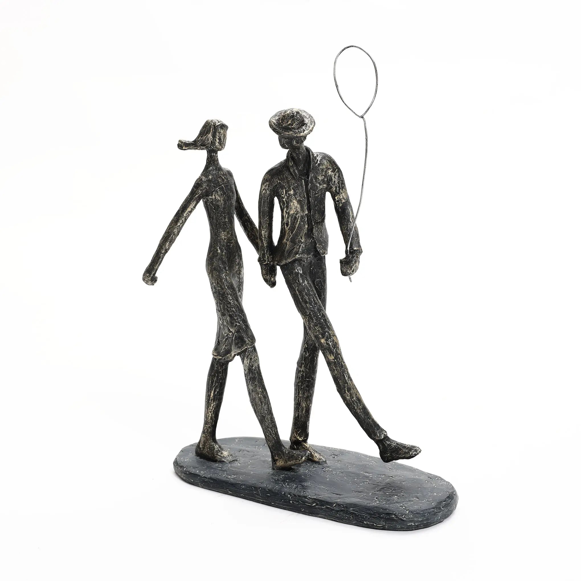 A modern resin sculpture of a couple walking hand in hand. The man holds a wire balloon. The figures are elongated and stylized, mounted on an oval base—a perfect home decoration for contemporary spaces.