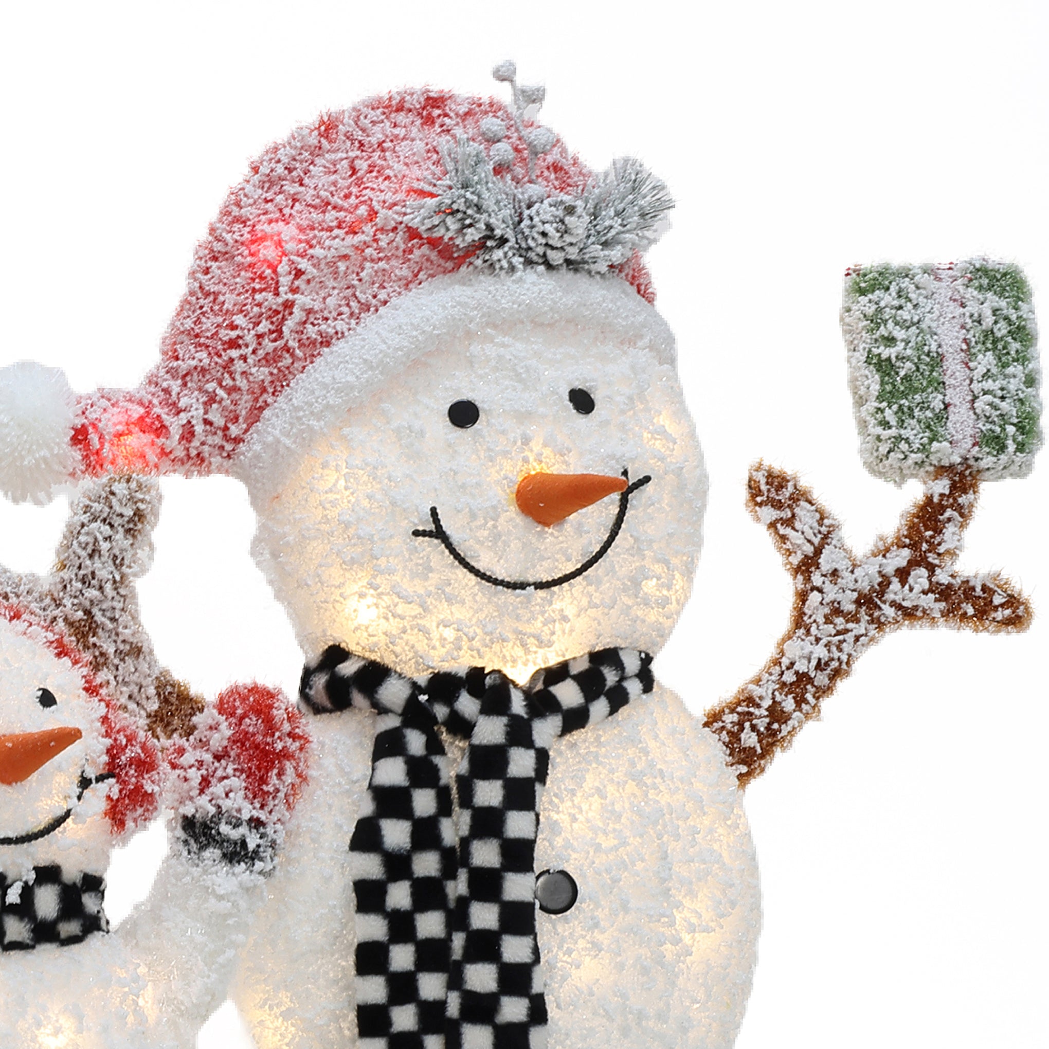 A smiling snowman wearing a red Santa hat and a black-and-white checkered scarf holds a green gift box covered in snow—perfect as an outdoor Christmas decor snowman decoration.