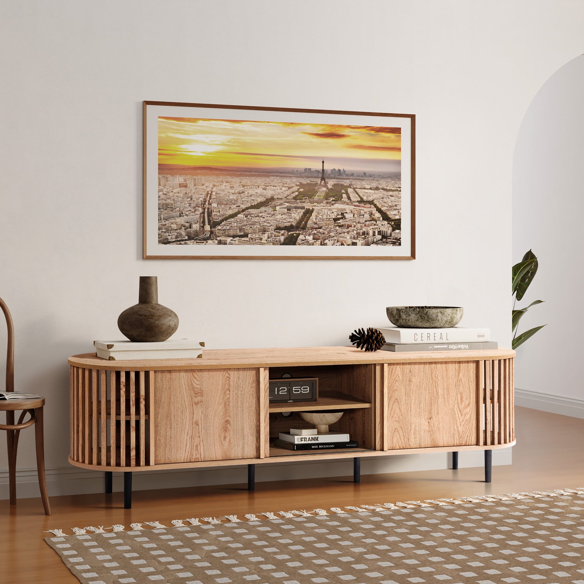A modern living room showcases a wooden console with a vase, book, and bowls. Above it hangs a large cityscape photo at sunset. A patterned rug accents the floor, complemented by a mid-century modern TV cabinet seamlessly integrating style and function.