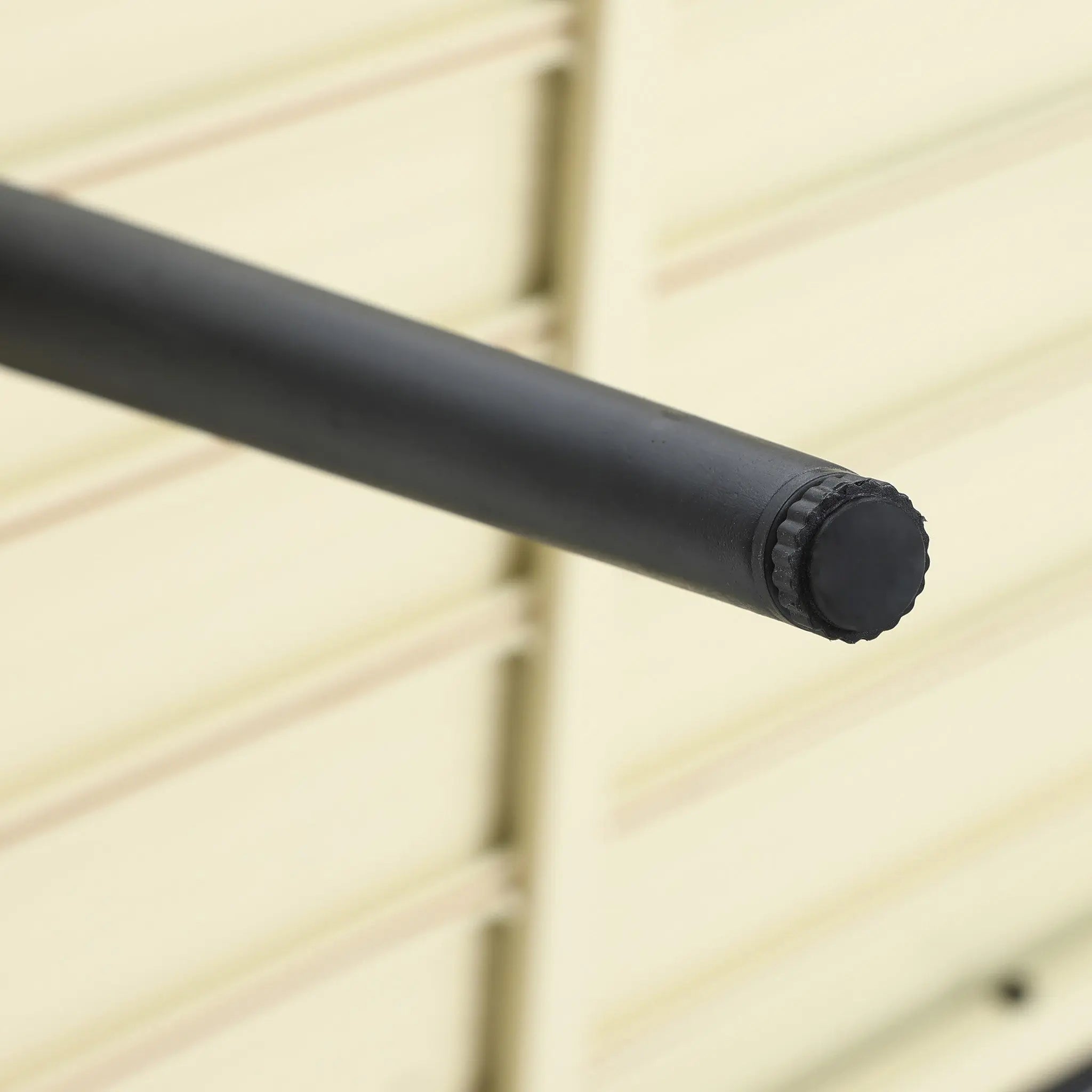 Close-up of a black cylindrical metal pipe extending horizontally, with a textured cap on the end, against a blurred light-colored background. This could be the perfect frame detail for your outdoor aluminum rattan sofa or as part of a sleek patio furniture set.