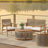 Outdoor patio set on a deck overlooking a calm lake, featuring an acacia wood sofa and chairs with plush cushions. The hand-woven rope circular coffee table and side table add charm to the decor, complemented by potted plants and candles. Perfect for indoor or outdoor relaxation.