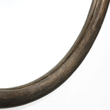A close-up of the Aged Wood Finish Crater Pattern Round Wall Mirror by LuxenHome features its dark frame against a white background. The textured surface gives an industrial-inspired rustic look.