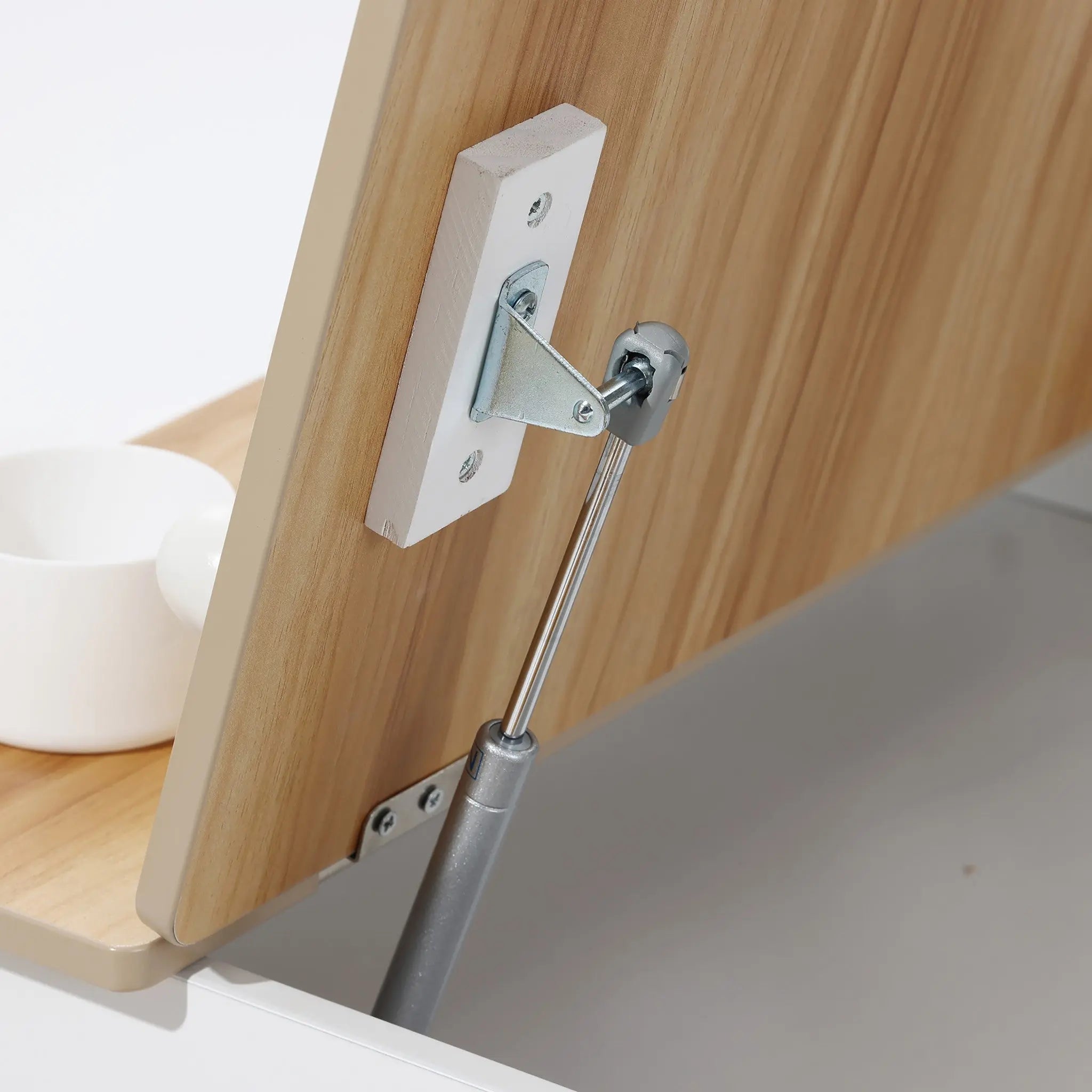 Close-up of the LuxenHome Activity Children Table with Storage Bookcase and 2 Chairs Set, featuring a hydraulic lift mechanism and metal hinge. A white cup is on the desk, highlighting its adjustability and ample storage for creative projects.