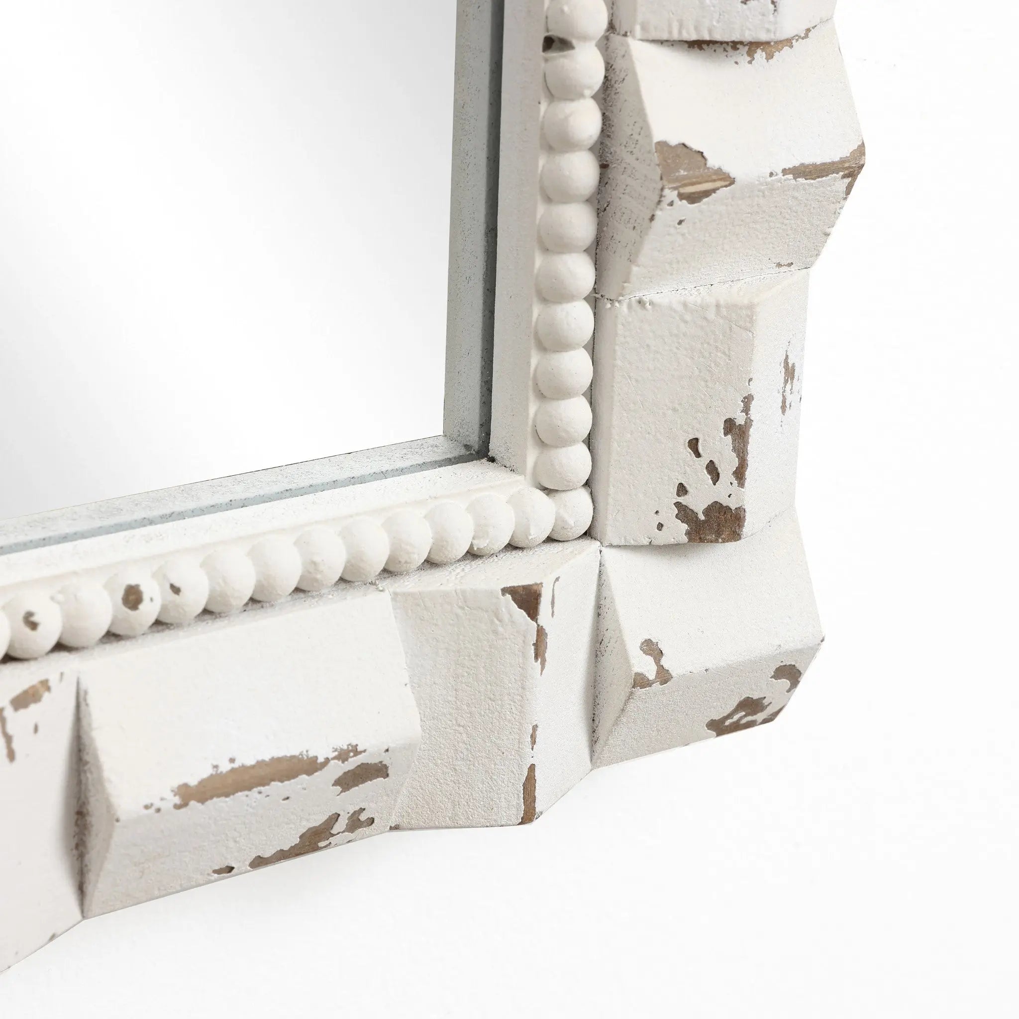 This arched rectangular mirror features a close-up of its corner, showcasing a distressed white wooden frame with ornate bead detailing, perfect for adding a touch of vintage charm to any home decoration.