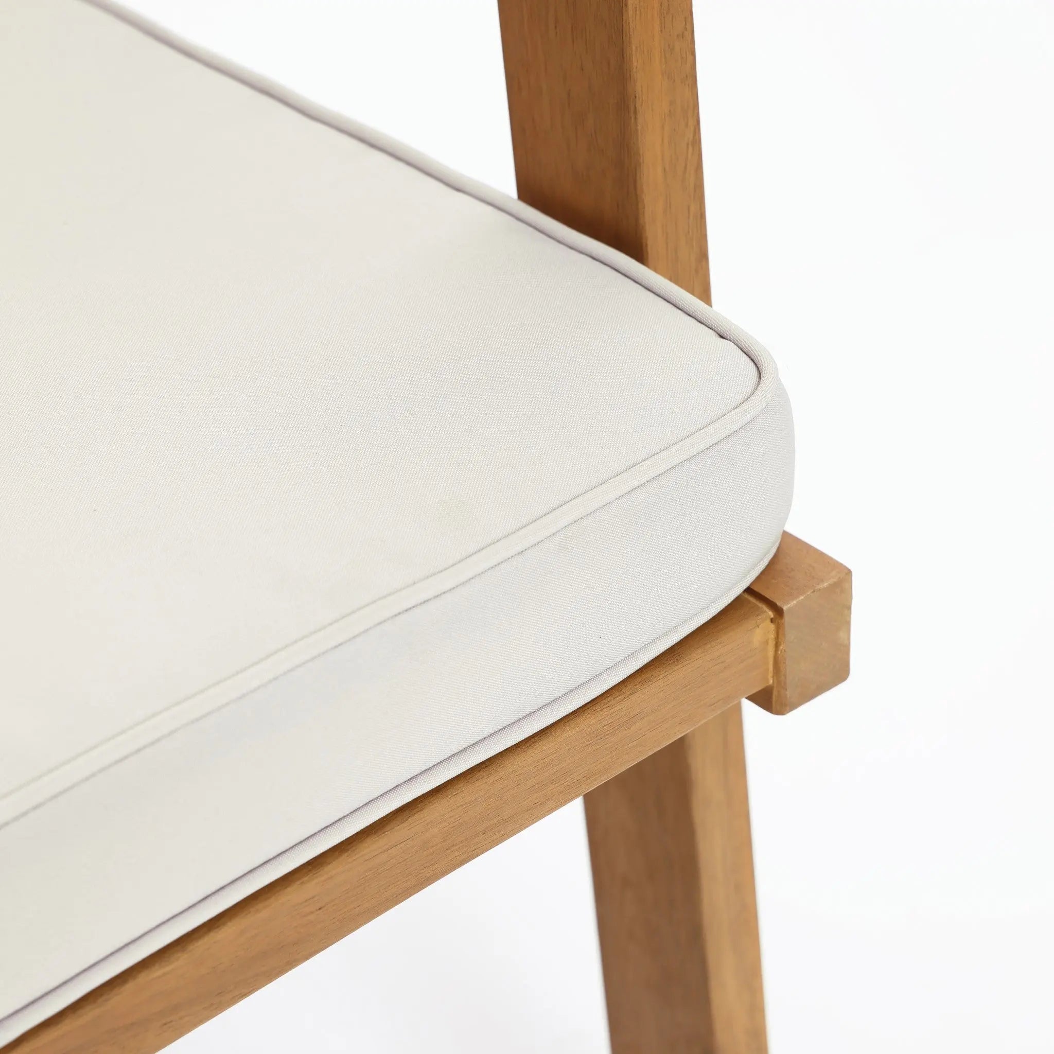 Close-up of a wooden chair with a white cushion, embodying minimalist design. The image focuses on the corner where the backrest and seat meet, highlighting the FSC-certified Acacia wood grain and the smooth fabric of the cushion.