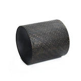 A black cylinder with intricate floral patterns rests elegantly on its side against a plain white background, complemented by a gold metal stand.