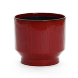 The LuxenHome burgundy red glazed ceramic planter, 11.61 h, features a glossy finish, wide rim, narrow base, and a subtle vertical stripe design against a plain white background, embodying elegance and timeless style.