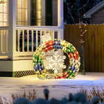 A large, colorful Christmas wreath with a snowflake design is displayed on a porch, its radiant outdoor lights reflecting off the fresh snow. This stunning holiday decoration brings festive cheer to the winter scene.