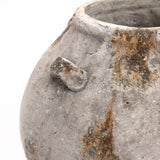 Close-up of an aged, weathered terracotta jug vase with a rough, textured gray surface and earthy brown patches. This handcrafted vintage vase features a small handle protruding from the side, making it a versatile home decor piece.