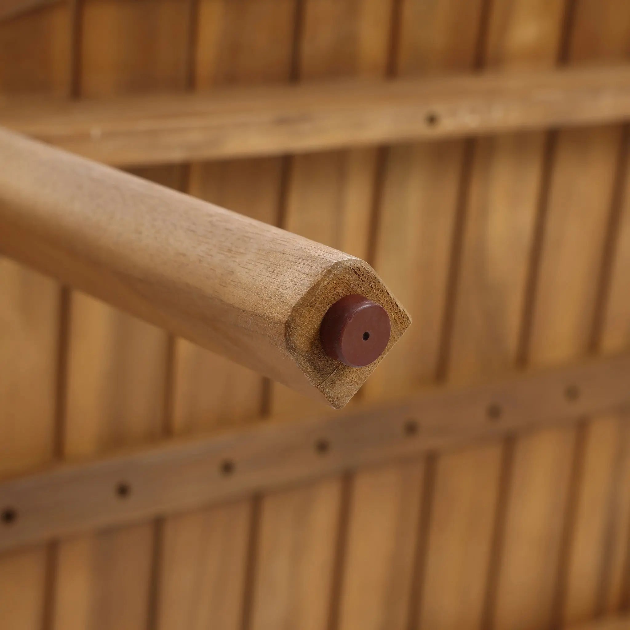 Close-up of the end of a wooden oar with a reddish-brown cap, positioned above the acacia wood planks of a boat interior, evoking the craftsmanship found in an outdoor Acacia Wood Coffee Table Set.