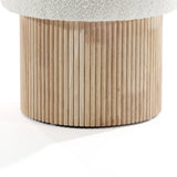 Close-up of the wooden cylindrical base of the LuxenHome Mina boucle and wood storage ottoman, featuring vertical grooves. The top shows part of the light fabric-covered cushion, highlighting its elegant appearance through textures and materials.