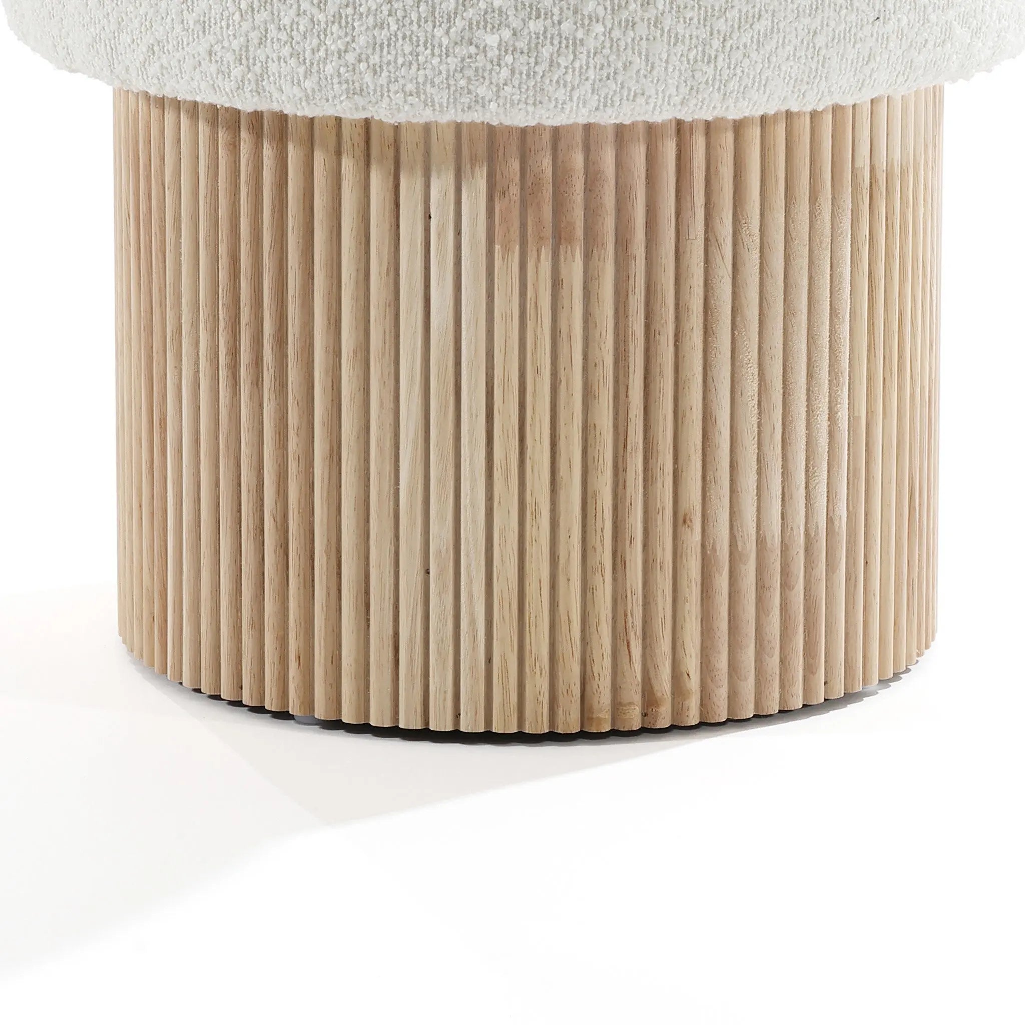 Close-up of the wooden cylindrical base of the LuxenHome Mina boucle and wood storage ottoman, featuring vertical grooves. The top shows part of the light fabric-covered cushion, highlighting its elegant appearance through textures and materials.