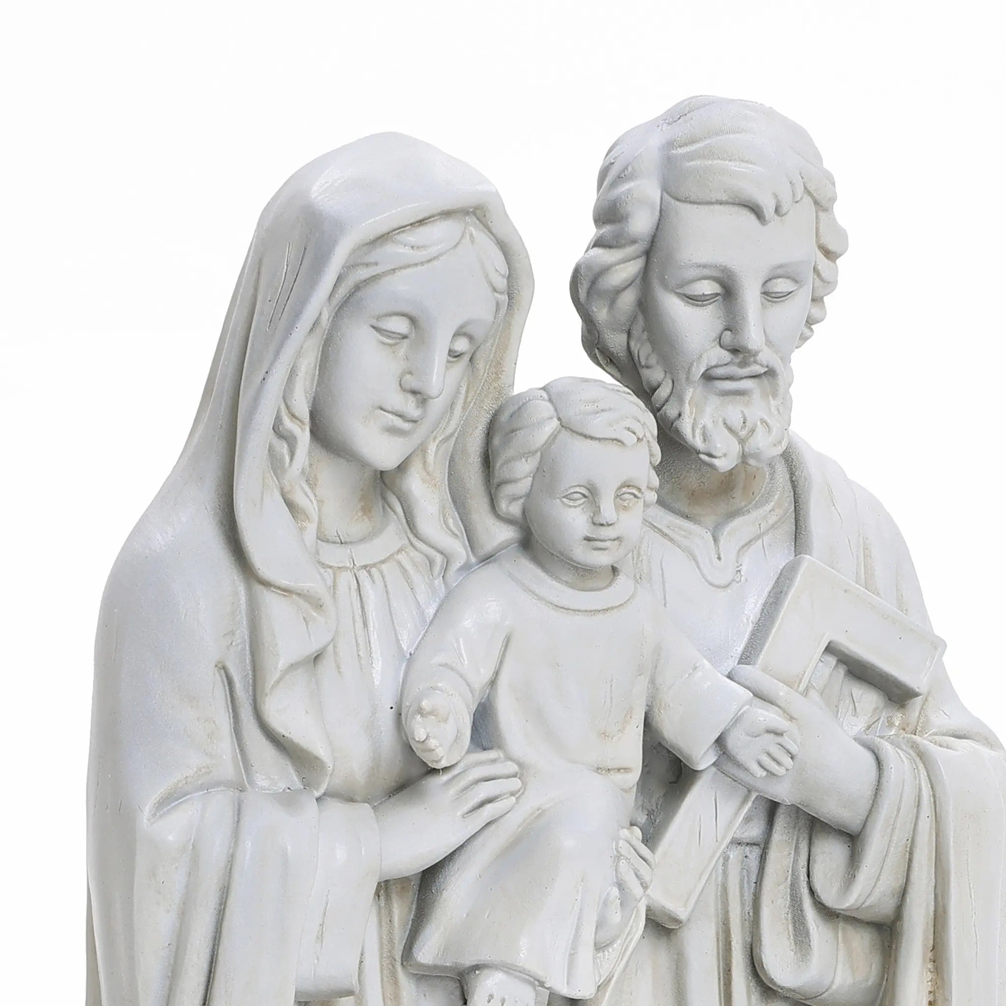 A white, marble-like polyresin sculpture portrays three figures: a seated child in the center, flanked by a woman holding the child and a man with a carpenters square, embodying the essence of religious decor as a Holy Family statue.