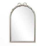 A Ribbon Wall Mirror featuring an arched silhouette and a decorative bow atop its ornate silver frame, perfectly complements a modern romantic style against a plain white background.