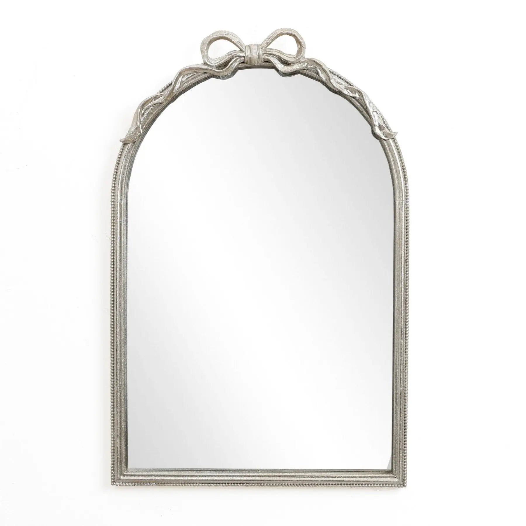A Ribbon Wall Mirror featuring an arched silhouette and a decorative bow atop its ornate silver frame, perfectly complements a modern romantic style against a plain white background.