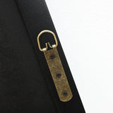 Close-up of a brass D-ring picture hanger attached to the back of a black frame with three screws, embodying a modern aesthetic against a white background.