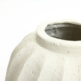 Close-up of a textured, unglazed ceramic pot with a wide opening, serving as an artistic centerpiece against a plain white background. Ideal for those seeking minimalist home decor to enhance their space.