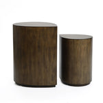 Two brown, cylindrical wooden stools of different heights exude rustic charm as they sit side by side on a white background, reminiscent of mid-century modern design.