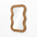 A modern vibe emanates from the wavy-edged rectangular wall mirror, its natural cork wood frame contrasting elegantly against the plain white background.
