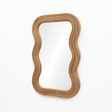 A modern vibe emanates from the wavy-edged rectangular wall mirror, its natural cork wood frame contrasting elegantly against the plain white background.