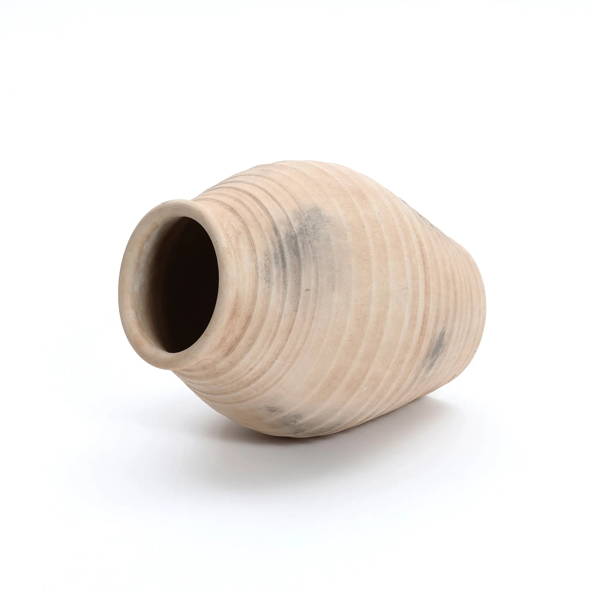 The LuxenHome Rustic beige ribbed terracotta urn vase, 13.2 h, showcases a handcrafted, round-bottom design with a wide opening and ribbed texture, elegantly displayed on its side against a crisp white background.