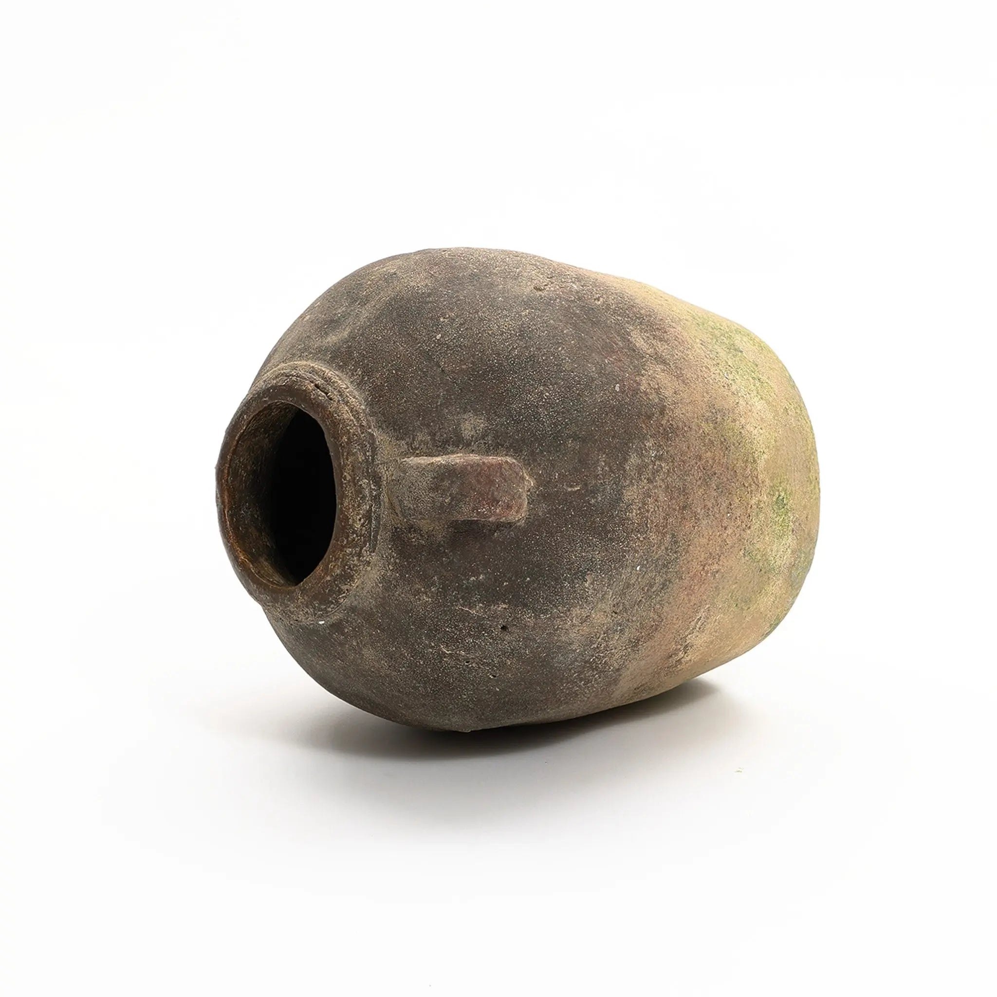 Aged, weathered ceramic jar with a wide mouth lies on its side against a plain white background, showcasing its handcrafted weathered finish. This rustic terracotta vase is perfect for any indoor and outdoor urn arrangement.
