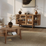 A cozy living room highlights a wooden coffee table with a vase and open book, paired with the LuxenHome Miko sideboard server cabinet featuring solid wood legs filled with decor items. A modern painting, botanical arrangement, and textured rug enhance the warmth and style of the neutral-toned space.