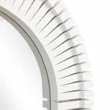 Close-up of a round wall mirror with a layered, geometric frame featuring evenly spaced ridges in a light pastel color. Perfect for adding a touch of stylish home decor to any room.