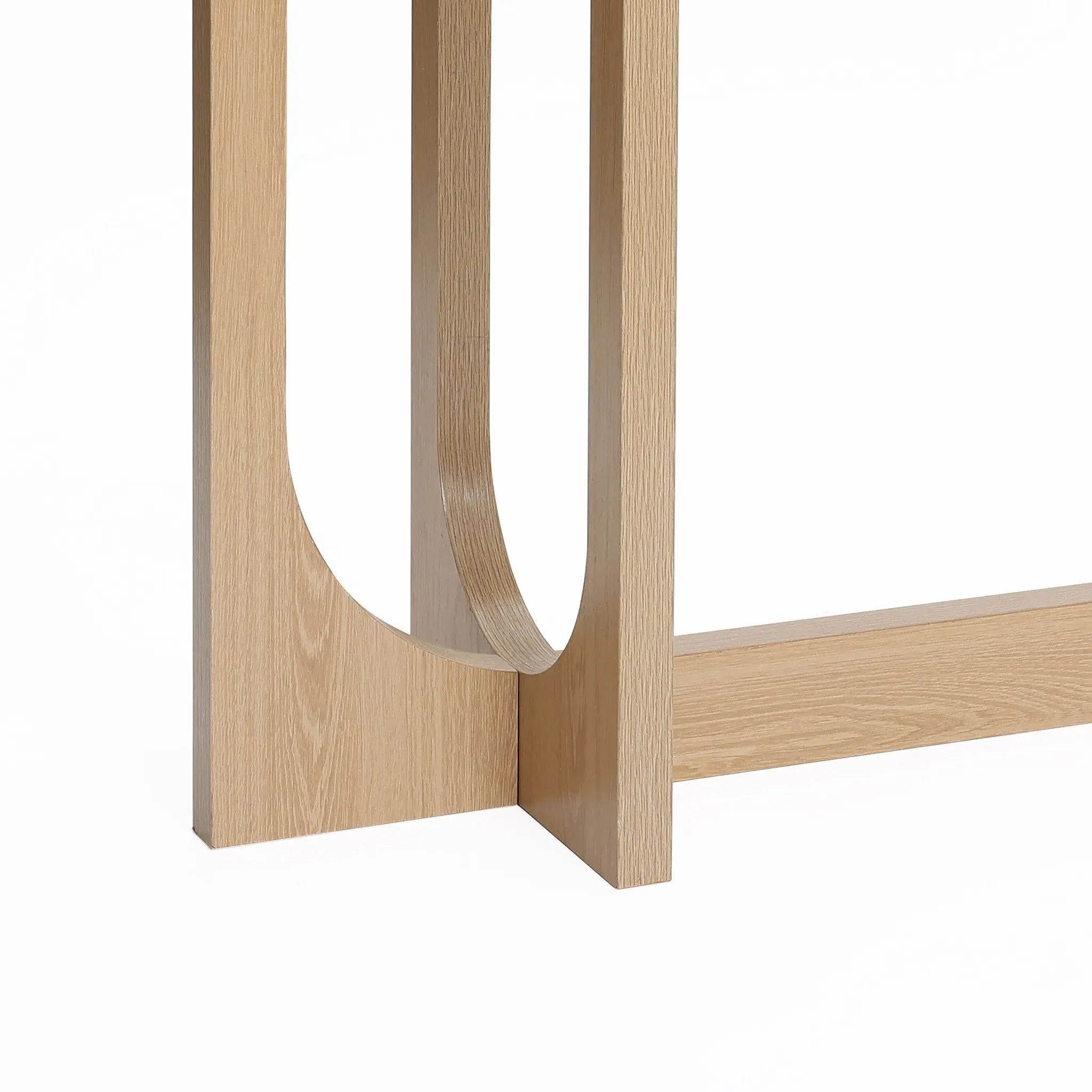 A close-up of the Lorean console table leg by LuxenHome showcases its modern design with a smooth natural wood finish and a distinct curved cutout, lending a minimalist and contemporary touch to this stylish piece.
