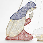 A woven light-up figure of a kneeling woman features a blue head covering, white robe, and red sleeves and skirt. Enhanced with LED bulbs to shine brightly, this enchanting Christmas decoration evokes the guiding light of the North Star.
