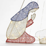 A woven light-up figure of a kneeling woman features a blue head covering, white robe, and red sleeves and skirt. Enhanced with LED bulbs to shine brightly, this enchanting Christmas decoration evokes the guiding light of the North Star.