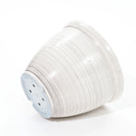 A stack of sleek, white disposable paper plates on a minimalist white background, viewed from the side, reminiscent of a contemporary planter design.