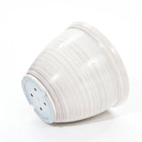A stack of sleek, white disposable paper plates on a minimalist white background, viewed from the side, reminiscent of a contemporary planter design.